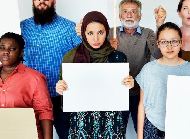 A diverse group of people holding signs advocating for various human rights causes, representing the liberal perspective on human rights activism and international law.