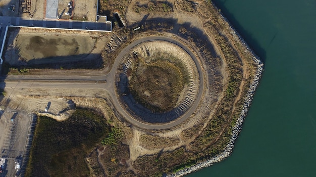 An aerial view of a pumped hydro storage facility, showing the upper and lower reservoirs connected by a series of pipes and turbines. The surrounding landscape is lush and green, highlighting the environmental considerations of such installations.