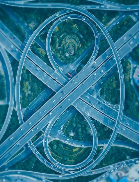 A split image showing the interior of an American factory on one side and a Chinese manufacturing plant on the other, connected by a winding road symbolizing trade routes.