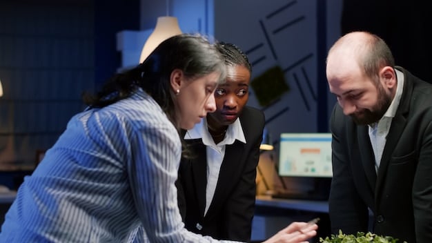 A diverse group of business professionals in a modern office collaborating around a digital display, illustrating strategic planning and teamwork in response to economic shifts.