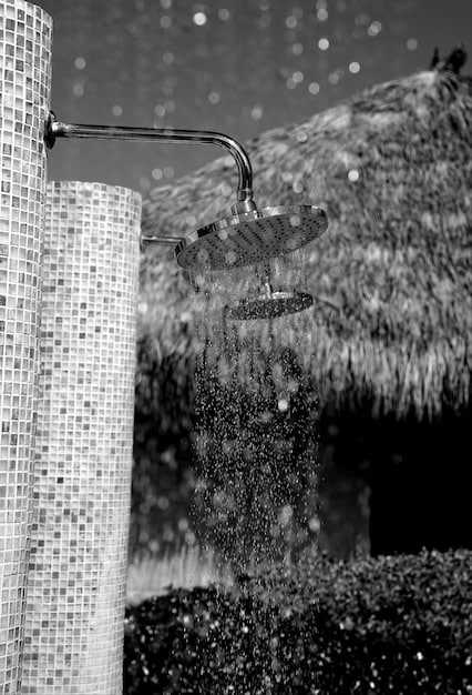 A low-flow showerhead spraying water, with steam rising in a well-lit modern bathroom. The focus is on the efficient water droplets, suggesting innovation and savings.